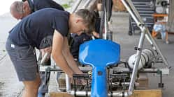 Jugendliche und Erwachsene montieren Steuerseile an einem Flugzeugprojekt im Rahmen eines OUV-Jugendprojekts.