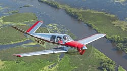Beechcraft Bonanza im Flug über eine Flusslandschaft bei AirVenture Oshkosh 2021, Wisconsin.