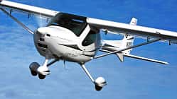 Das Foto zeigt ein Remos GX Leichtsportflugzeug (Light Sport Aircraft) im Flug. Der Hochdecker in Verbundbauweise besitzt ein Bugradfahrwerk und wird laut IPTC von einem 100‑hp Rotax 912 angetrieben. Die Aufnahme zeigt die Maschine über dem Beaver Lake bei Rogers, Arkansas (USA).