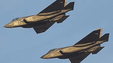 Zwei moderne Militärjets fliegen nebeneinander am Himmel.