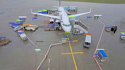 Flughafen, Flugzeug, Rollfeld, Bodenfahrzeuge, Objekterkennung, Luftfahrt, Gepäckwagen, Bodenpersonal Ein Flugzeug steht auf dem Rollfeld eines Flughafens und wird von verschiedenen Bodenfahrzeugen und Personal umgeben. Die Objekte sind mit farbigen Rechtecken und Beschriftungen markiert, vermutlich für eine automatische Objekterkennung.