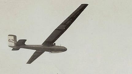 Rekordsegler Kegel, Segelflugzeug, Deutsches Segelflugmuseum, Historische Luftfahrt, Segelflug, Schwarzweißfoto, Archivaufnahme, Nummer 42, Oldtimer-Segler, Luftfahrtgeschichte Historische Schwarzweißaufnahme eines Rekordseglers im Flug, vermutlich aus dem Archiv des Deutschen Segelflugmuseums. Das Segelflugzeug ist von unten zu sehen, mit markanter langer Tragfläche und der Nummer 42 am Seitenleitwerk.