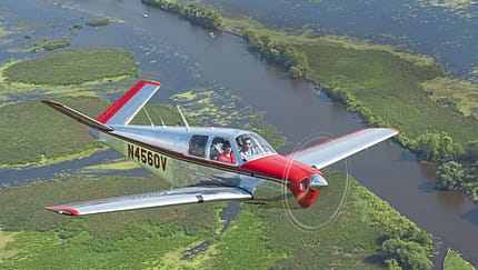 Beechcraft Bonanza im Flug über eine Flusslandschaft bei AirVenture Oshkosh 2021, Wisconsin.