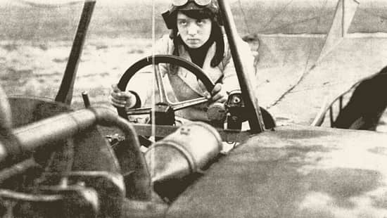 Historische Fotografie von Melli Beese im Cockpit eines Rumpler-Taube-Flugzeugs von 1911. Die Aufnahme zeigt die erste deutsche Frau mit Flugzeugführerschein am Steuer des Doppeldeckers.