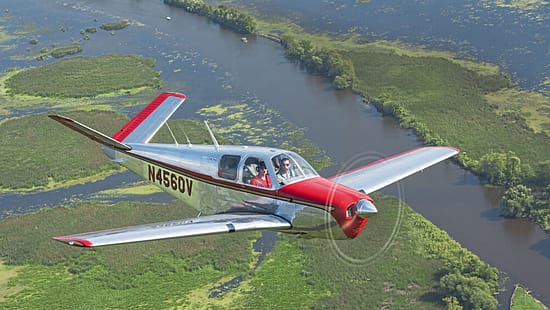 Beechcraft Bonanza im Flug über eine Flusslandschaft bei AirVenture Oshkosh 2021, Wisconsin.