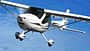 Das Foto zeigt ein Remos GX Leichtsportflugzeug (Light Sport Aircraft) im Flug. Der Hochdecker in Verbundbauweise besitzt ein Bugradfahrwerk und wird laut IPTC von einem 100‑hp Rotax 912 angetrieben. Die Aufnahme zeigt die Maschine über dem Beaver Lake bei Rogers, Arkansas (USA).