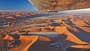 Luftaufnahme der Sossusvlei‑Wüste in Namibia, fotografiert aus einem Kleinflugzeug; der Flügel ist im oberen Bildbereich sichtbar. Die Szene zeigt weitläufige orangefarbene Sanddünen mit einzelnen ausgetrockneten Pfannen (u. a. Dead Vlei) und starkem Schattenwurf. Die Aufnahme entstand im Rahmen eines Rundflugs (Fly Unique), laut IPTC mit Hinweis auf eine Cessna als Trägerflugzeug.